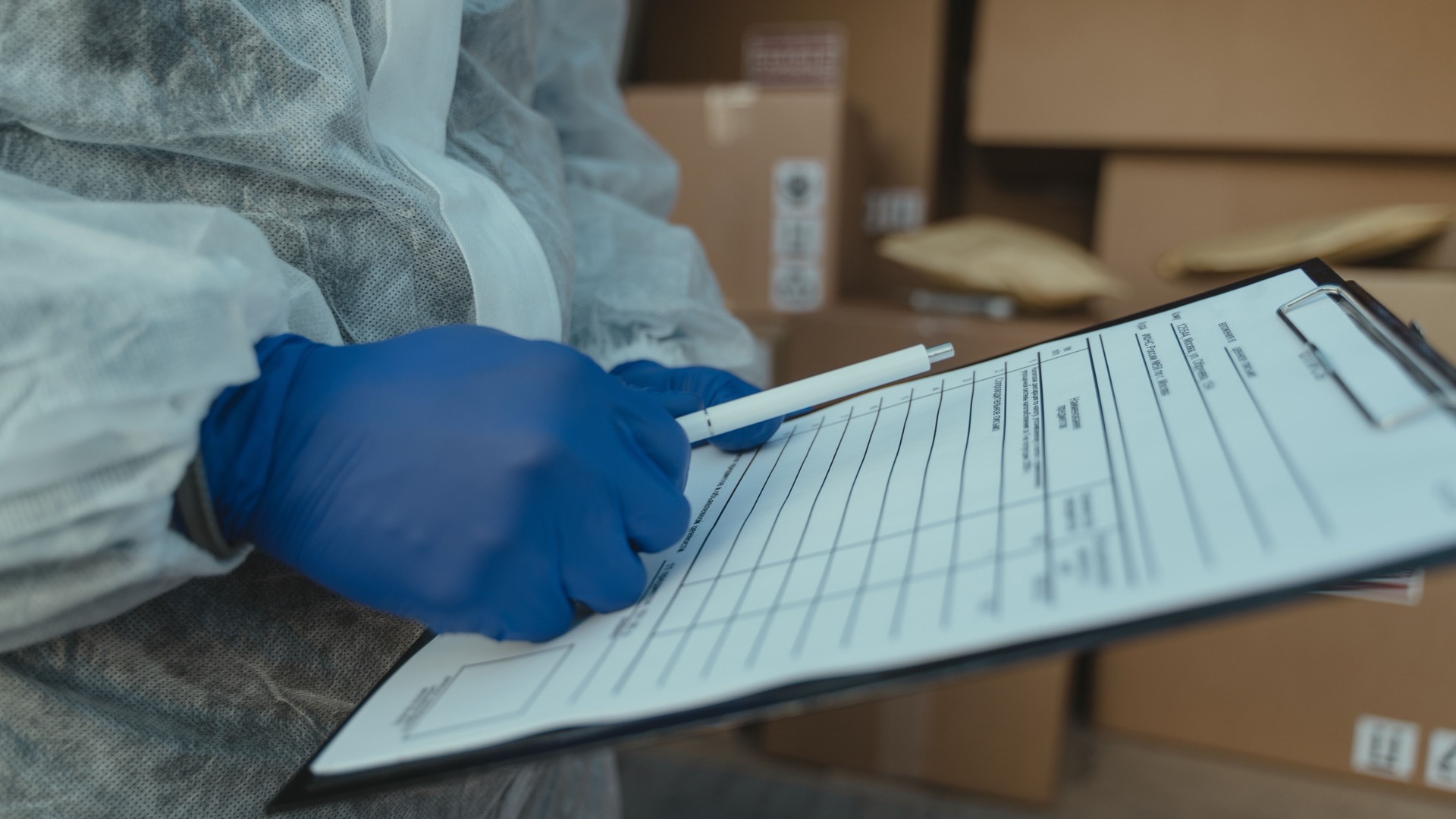 A gloved hand filling in a quality inspection form on a clipboard