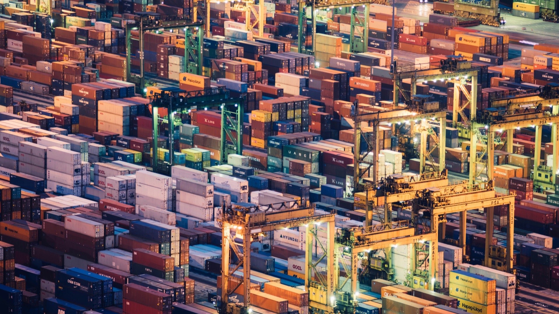 Aerial view of stacked shipping containers and cranes at a container port